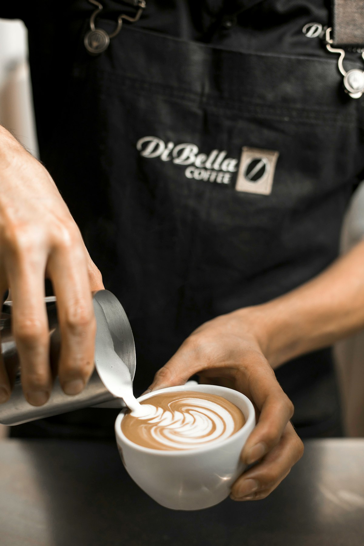 Barista pouring milk into a cup of coffee